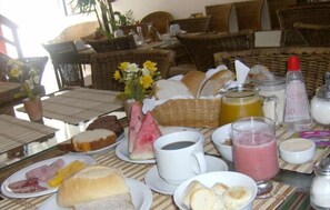 A breakfast table with bread, pastries, and a fruit bowl. - Quaraçá Pousada (Maceió)