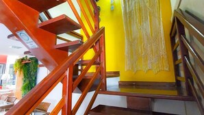 A wooden staircase with a yellow wall and a decorative curtain. - Quaraçá Pousada (Maceió)
