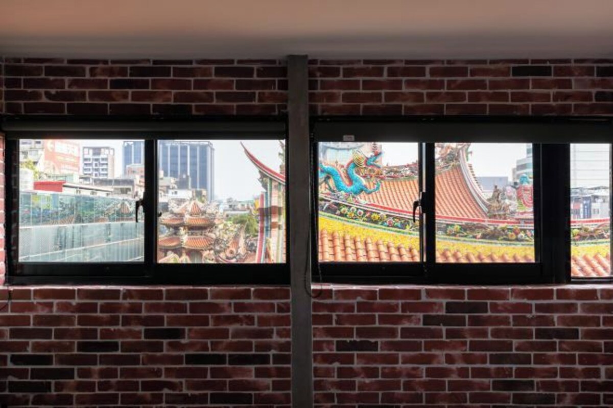 A room with a brick wall and two windows.
