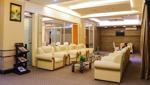 A hotel lobby with a reception area, seating arrangements, and a wall-mounted TV. - Hotel Afford Inn (Dhaka)