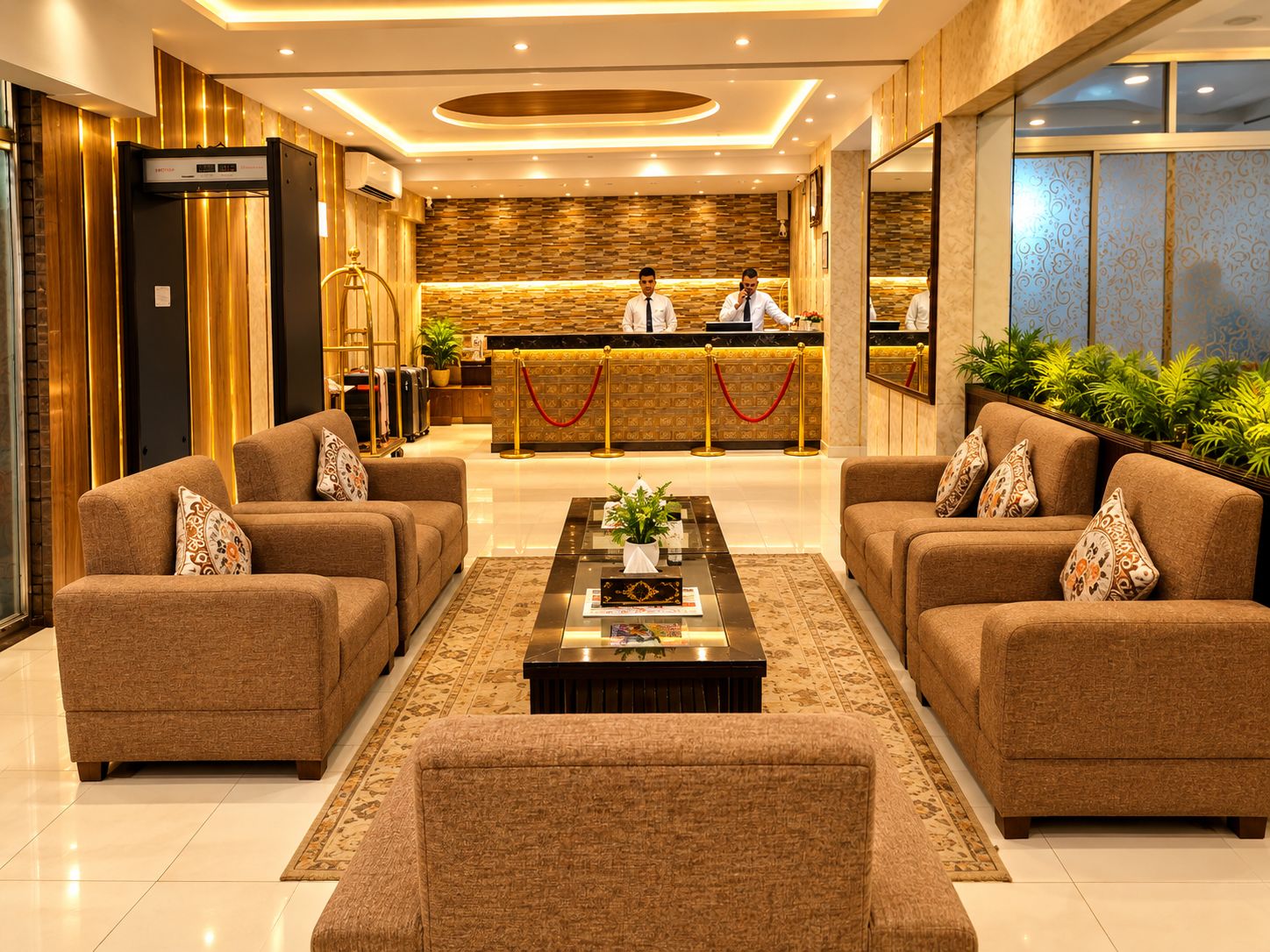 Een hotel lobby met een receptiebalie, twee banken, een bijzettafeltje en een grote spiegel.