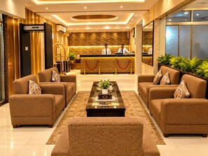 Um hall de hotel com balcão de recepção, dois sofás, uma mesa de centro e um espelho grande.