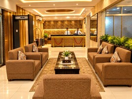 Un vestíbulo de hotel con un mostrador de recepción, dos sofás, una mesa de centro y un espejo grande.