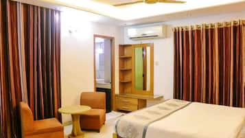 A hotel room with a bed, a small round table, a chair, a wardrobe, and a mirror.