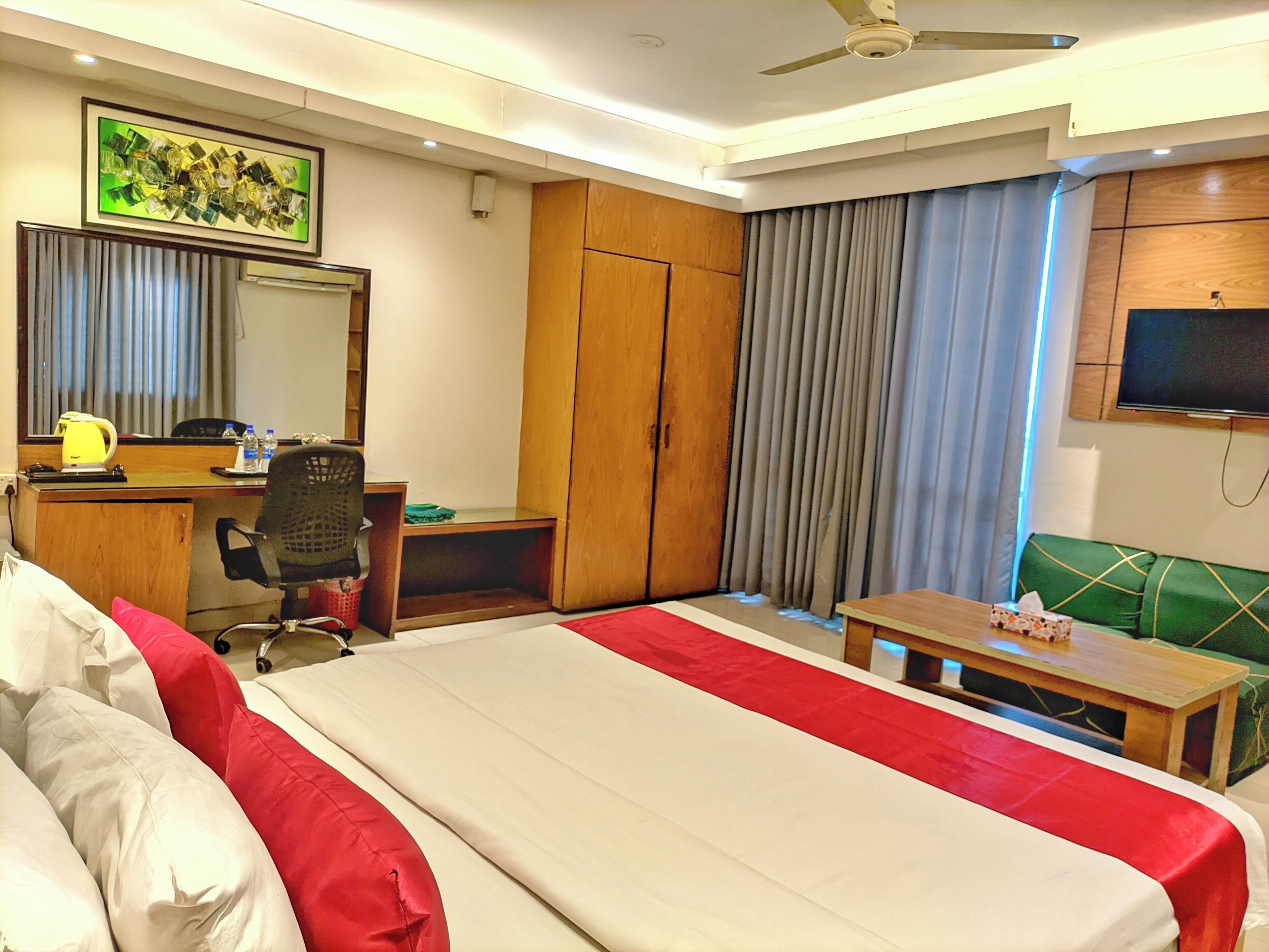 A hotel room with a bed, desk, chair, television, and curtains.