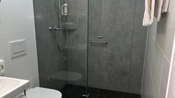 Une salle de bain moderne avec une douche à parois de verre, des toilettes et un lavabo.