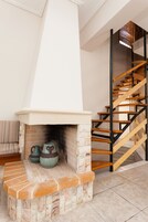 A fireplace with a stone surround, a wooden staircase, and a cushioned bench.