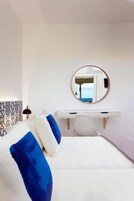 Una camera d'albergo con un letto, un comodino, uno specchio e vista sul mare.
