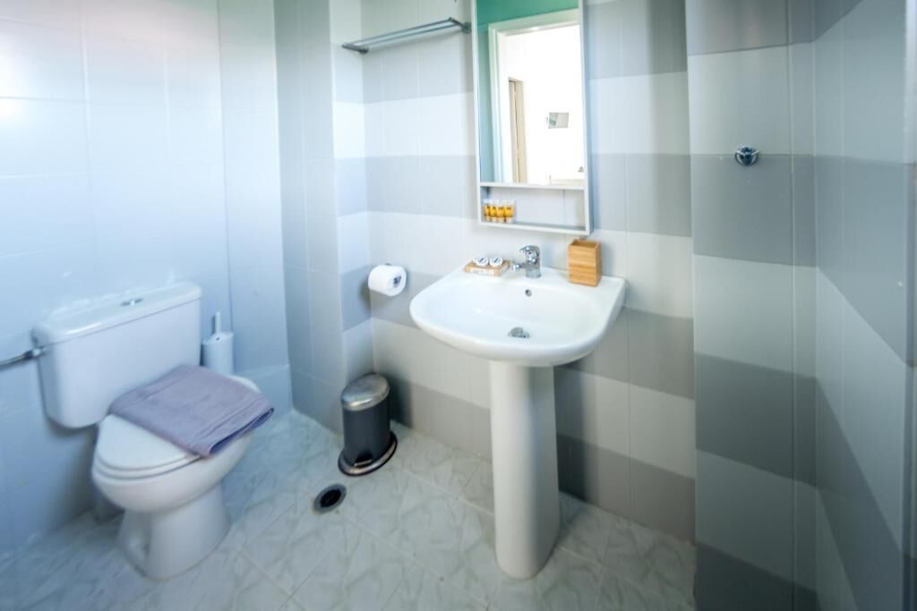 Een kleine badkamer met toilet, wastafel en spiegel.