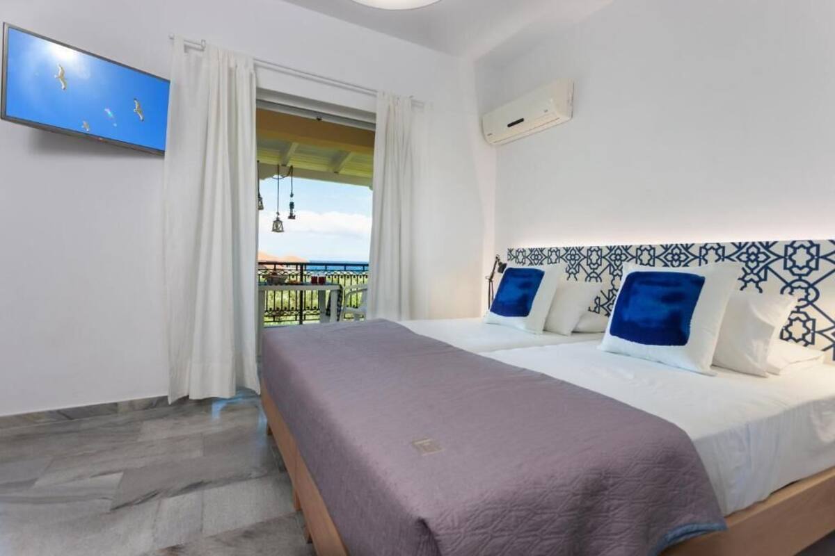 A hotel room with a bed, a TV, a balcony with a view, and a patterned headboard.