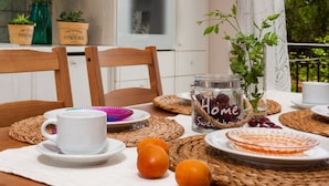 A dining table with a white cup, orange fruits, and a glass jar labeled "Home Sweet Home" with a plant. - Galatea (Zakynthos)