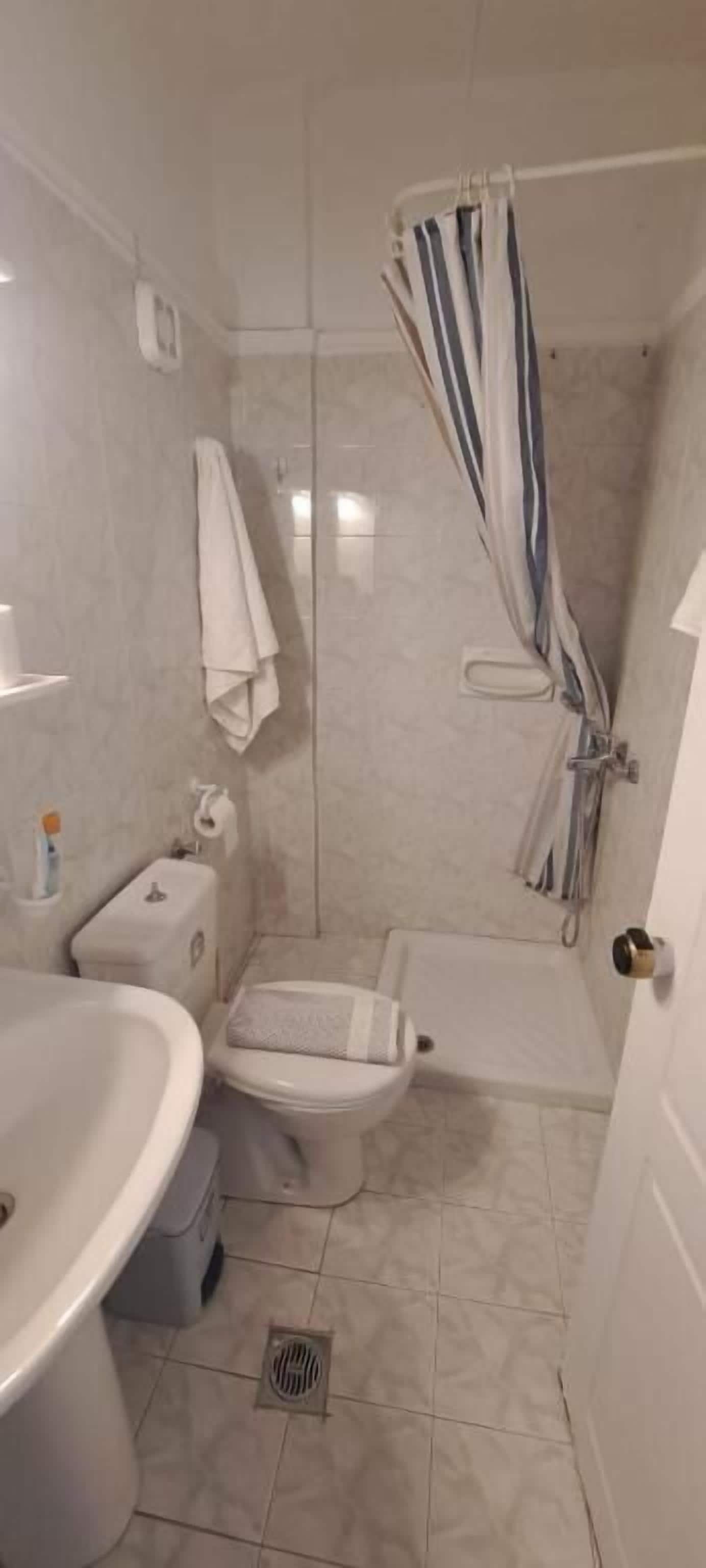 A small bathroom with a shower, toilet, and sink.