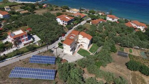 An aerial view of a coastal residential area with houses, a marina, and solar panels. - Galatea (Zakynthos)