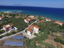 Una vista aerea di una zona residenziale costiera con case, un porto turistico e pannelli solari.