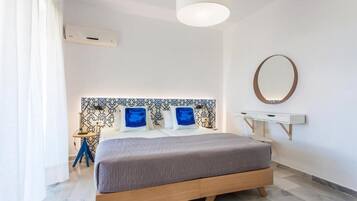 Un dormitorio moderno con cama, mesita de noche, lámpara y espejo en la pared.