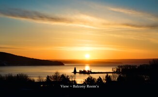 A sunset view from a balcony room with a lake and distant hills.