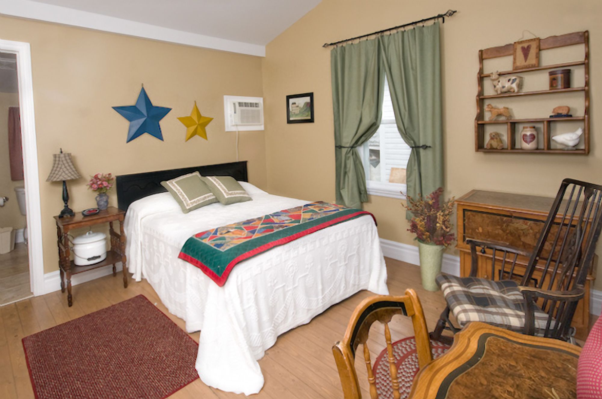 Une chambre à coucher avec un lit, une chaise, un bureau et une fenêtre avec des rideaux.
