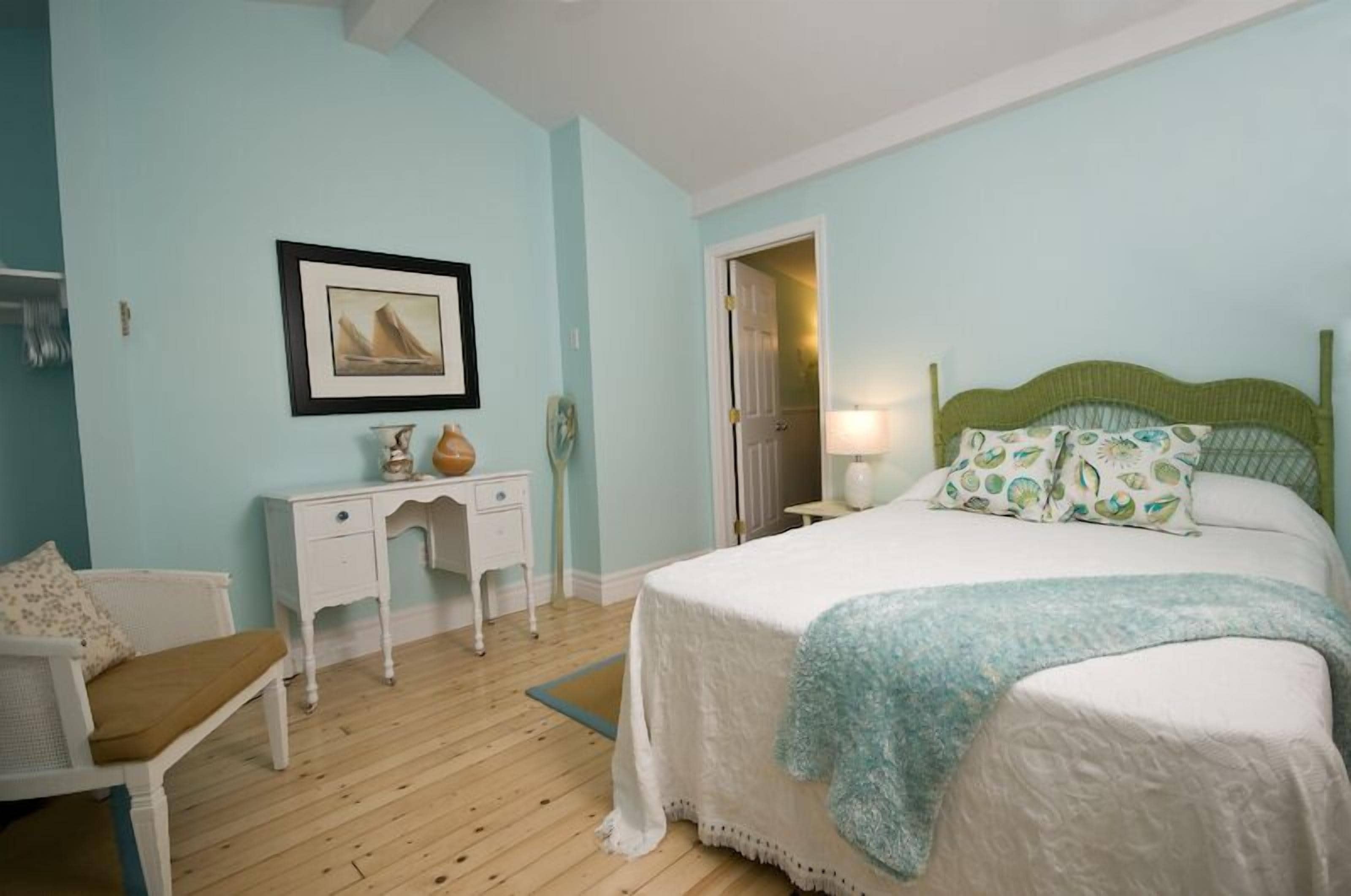 A bedroom with a bed, a desk, a chair, and a door.