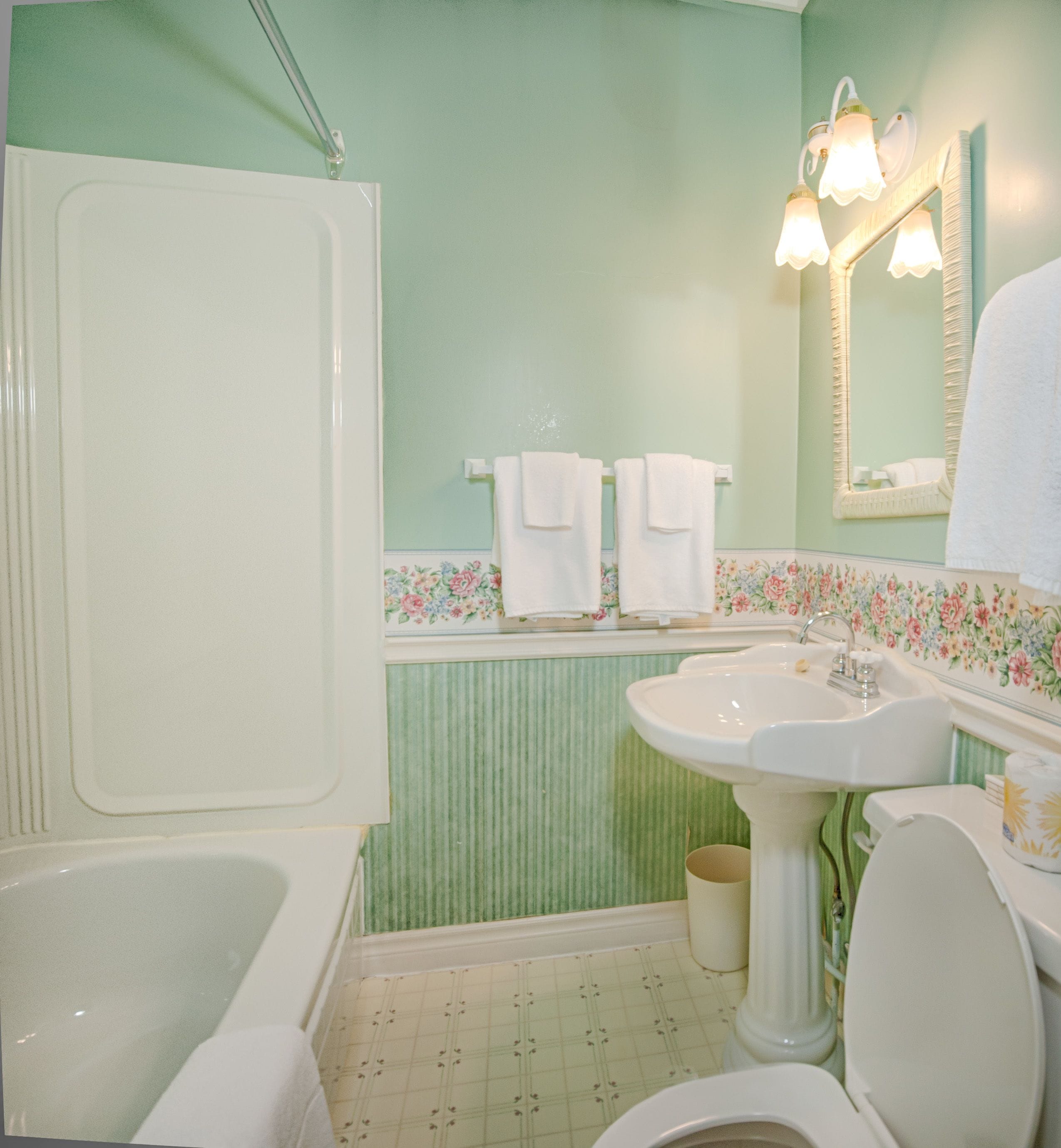 A bathroom with a bathtub, sink, toilet, and a mirror.