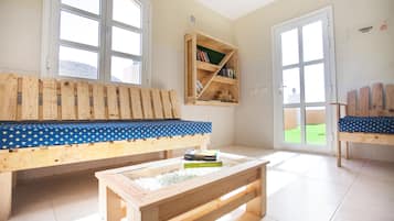A room with a wooden bench, a small table with books, and a bookshelf.