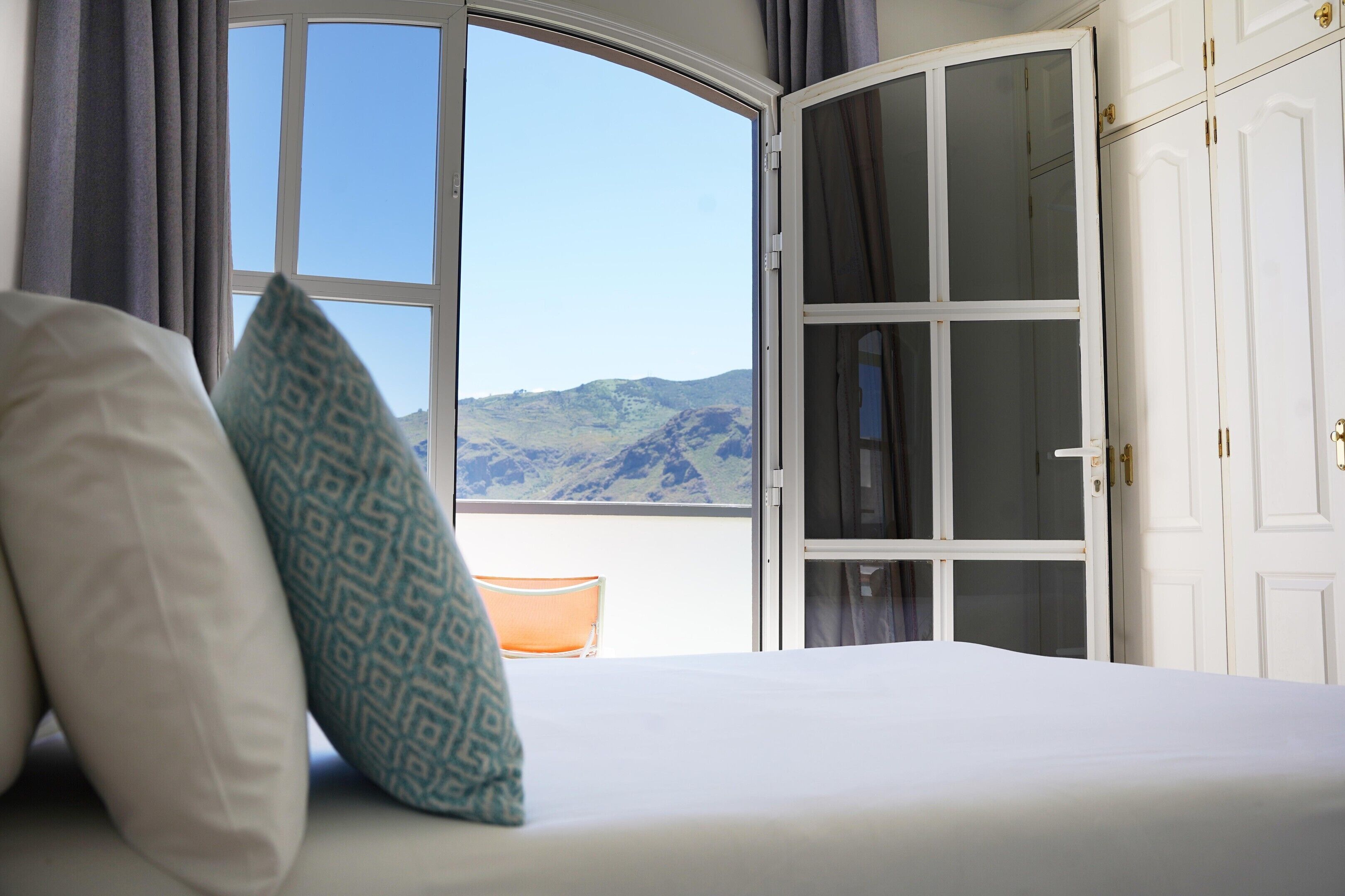 Un dormitorio con cama, ventana y vistas a las montañas, además de un armario.