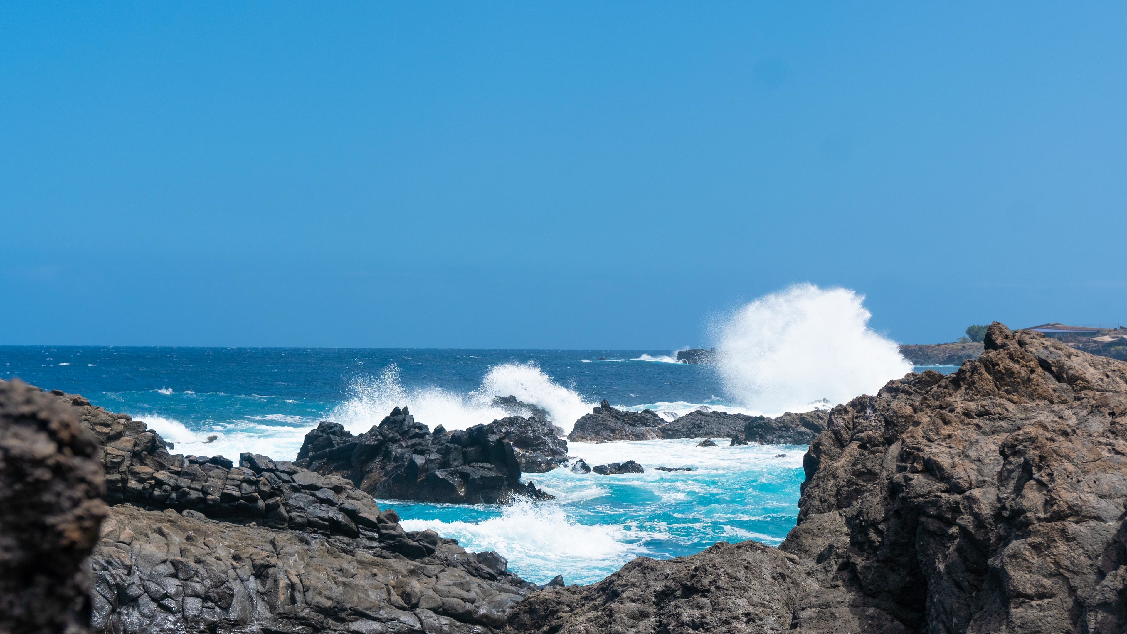 A rocky coastal landscape with waves crashing against the rocks.
