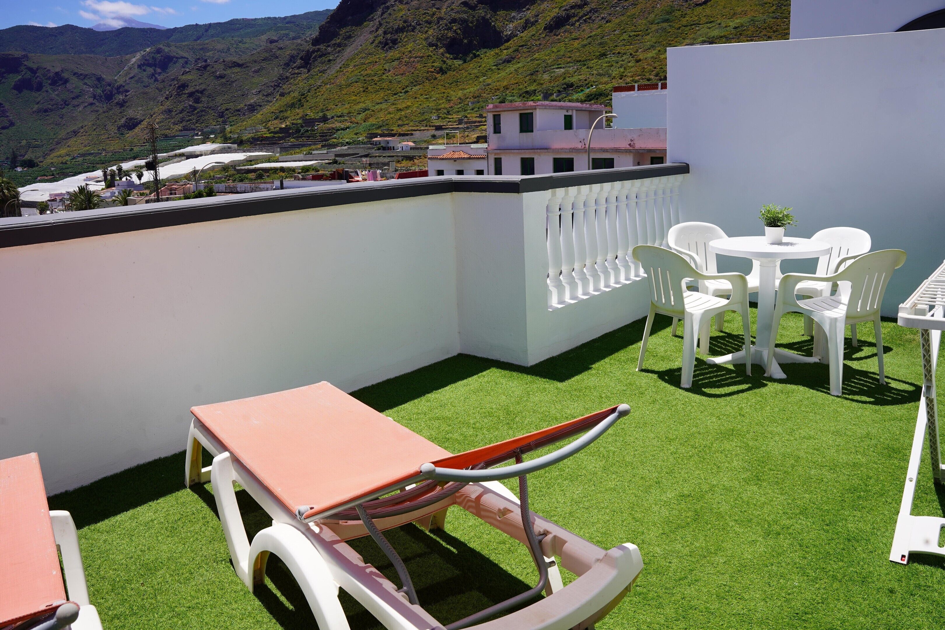 Une terrasse sur le toit, avec une table, des chaises et un fauteuil de relaxation.