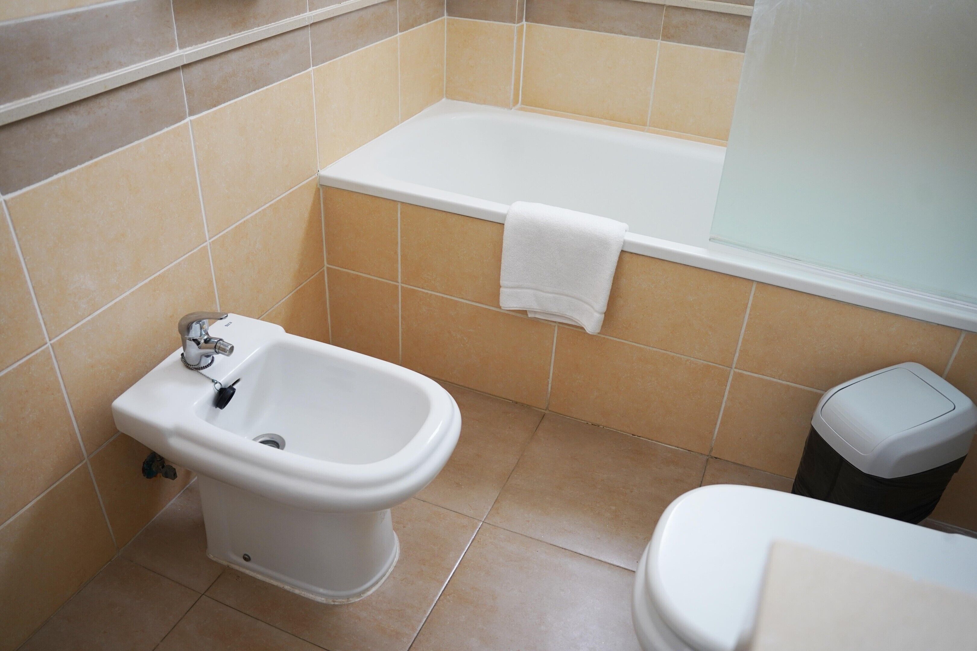 A bathroom with a bidet, a toilet, and a bathtub.