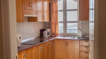 A kitchen with wooden cabinets, a window with curtains, a coffee maker, and a sink.