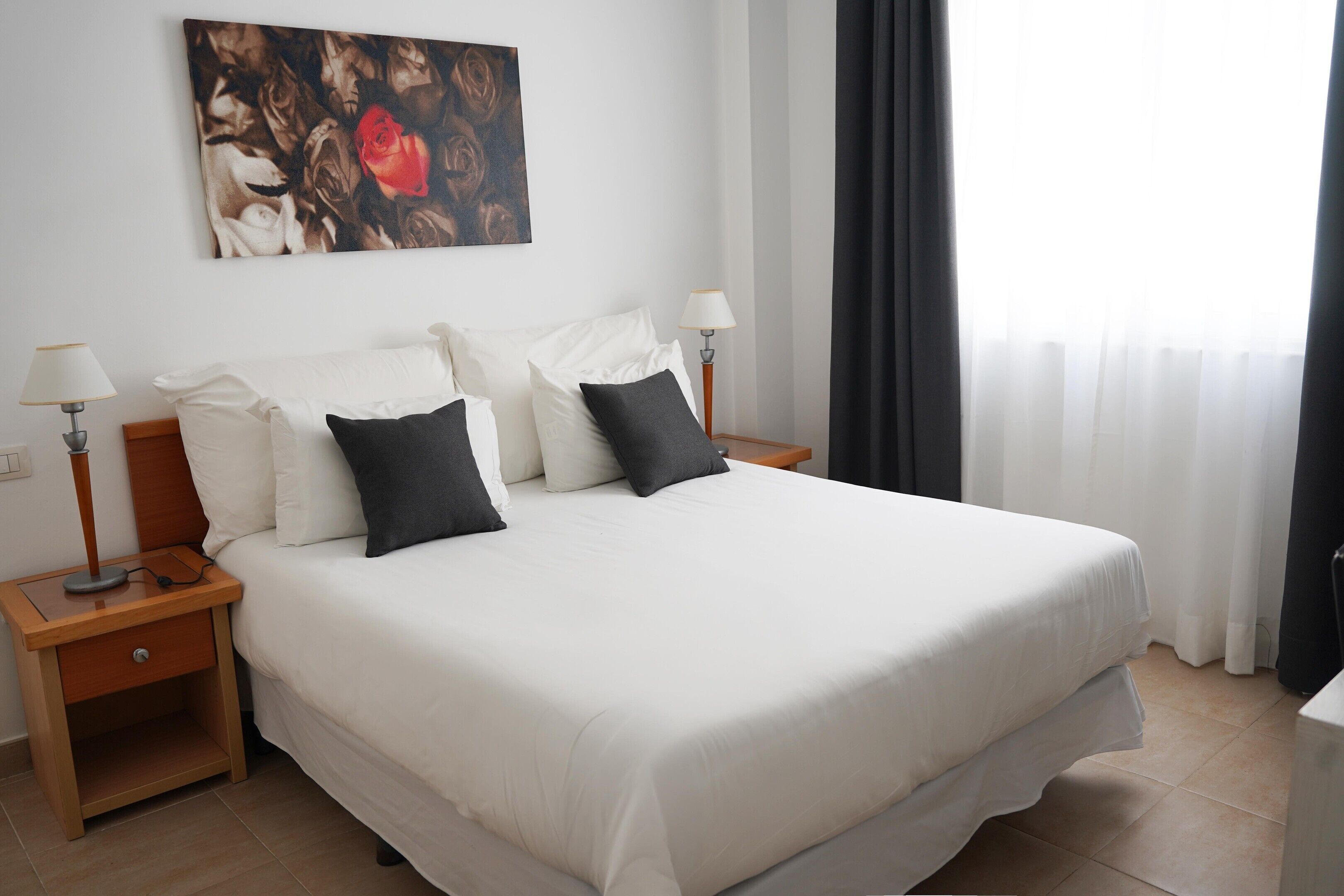 Una camera d'hotel con un letto grande, due comodini, una lampada e un quadro appeso al muro.
