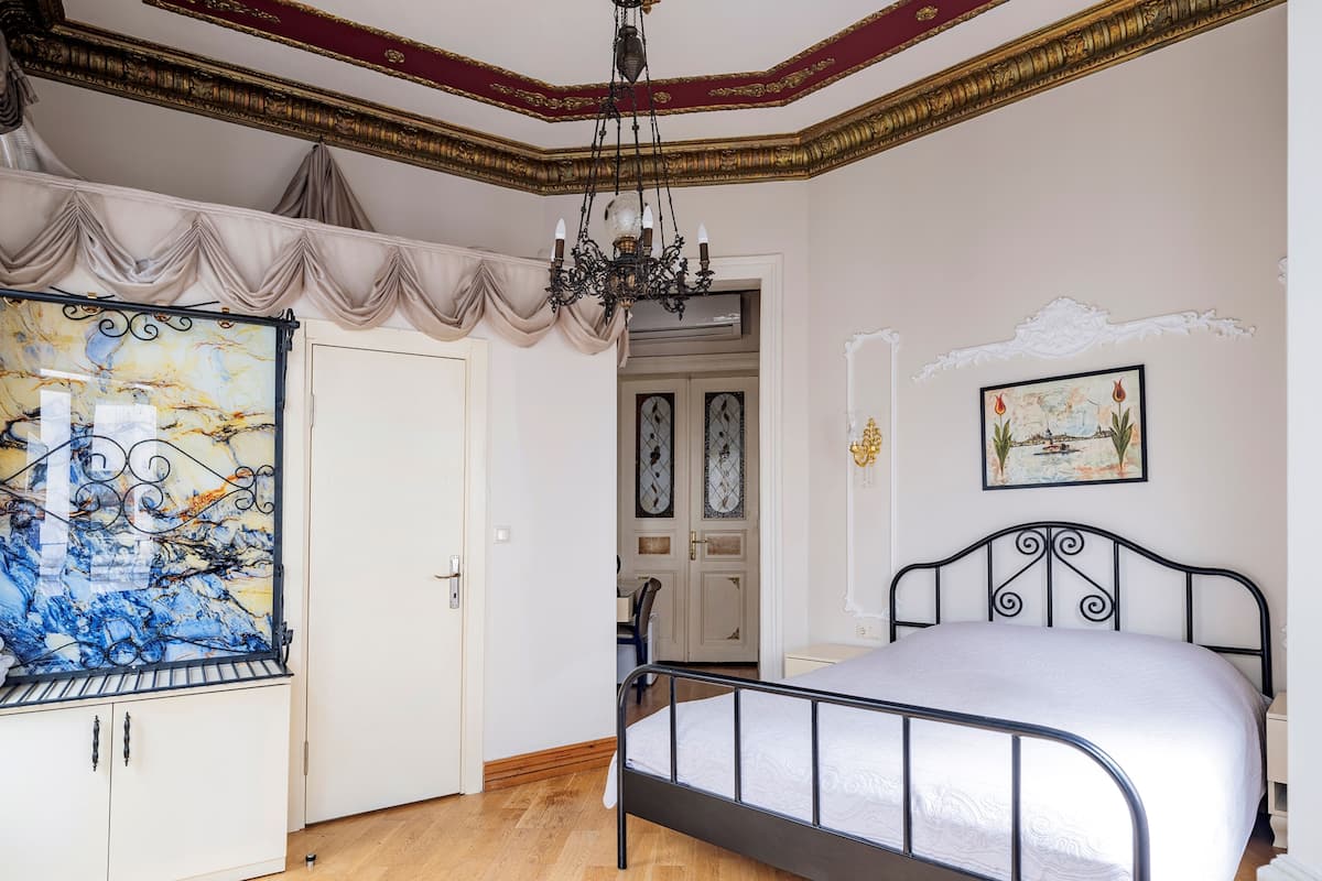 A bedroom with a bed, wardrobe, and a chandelier.