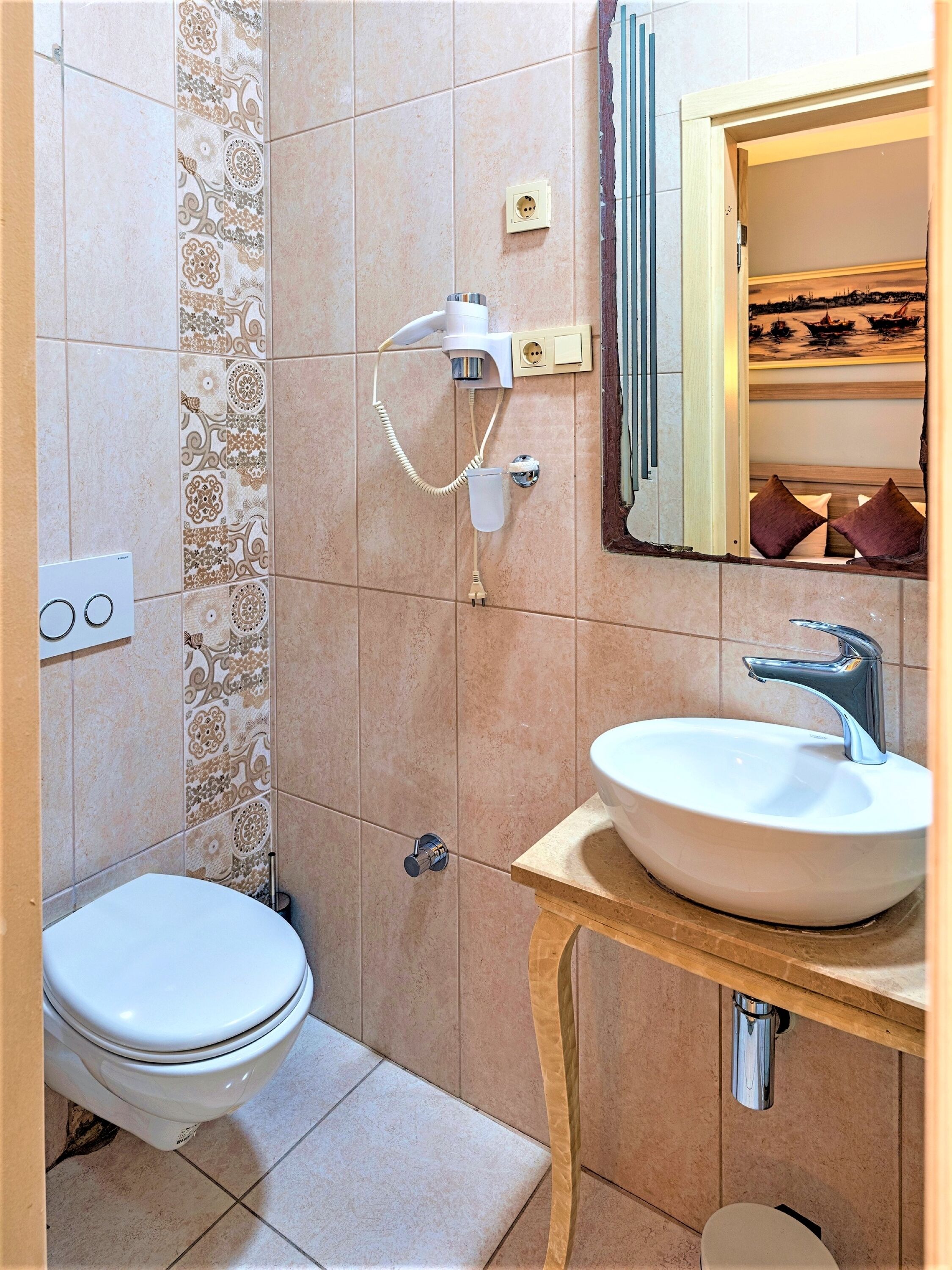 A bathroom with a toilet, a sink, and a hairdryer on the wall.