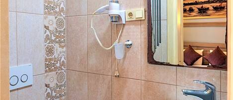 A bathroom with a toilet, a sink, and a hairdryer on the wall.