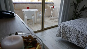 A hotel room with a bed, a dining table with chairs, a small balcony with a table and chairs, and a potted plant. - Apartamentos Pirámides (Arona)