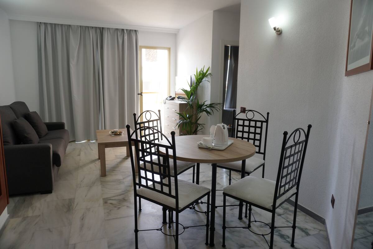 A modern living room with a sofa, dining table, chairs, and a coffee table.
