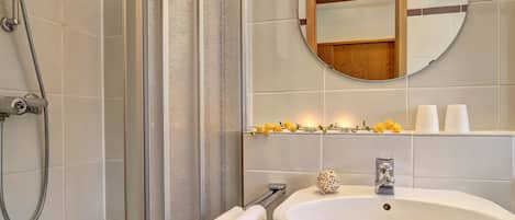 A modern bathroom with a glass-enclosed shower, a white sink, and a mirror above it.