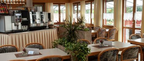 A restaurant with a bar area, multiple tables, chairs, and a large potted plant.