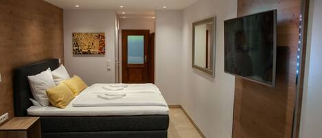 Una habitación de hotel moderna con una cama, un televisor y una pared de acento de madera.