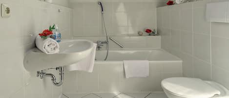 A modern bathroom with a skylight, a bathtub, a toilet, and a sink.