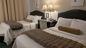 Habitació d'hotel amb dos llits, una taula de treball, una cadira i una làmpada.