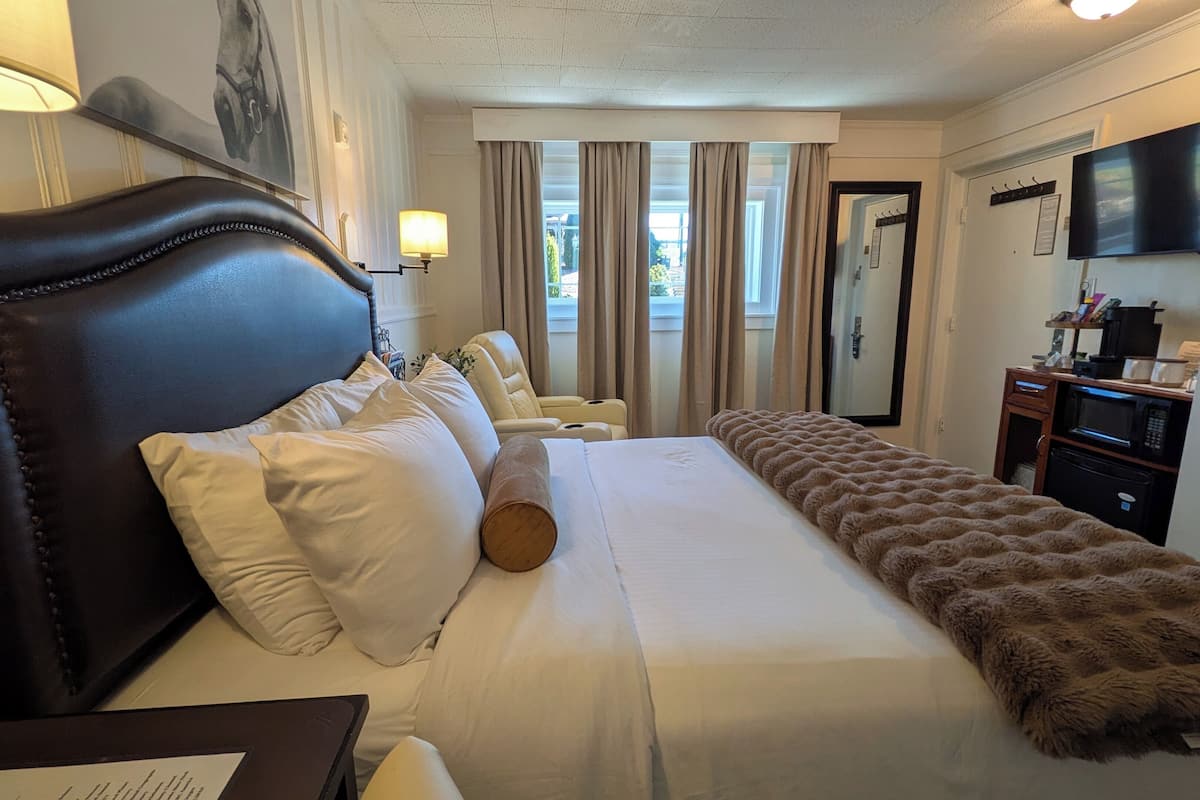 Une chambre d’hôtel avec un grand lit, un fauteuil massant, une télévision et une kitchenette.