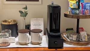 Una zona de cafè amb una màquina de cafè, dues tasses, un recipient de vidre i un safata amb diversos aliments.