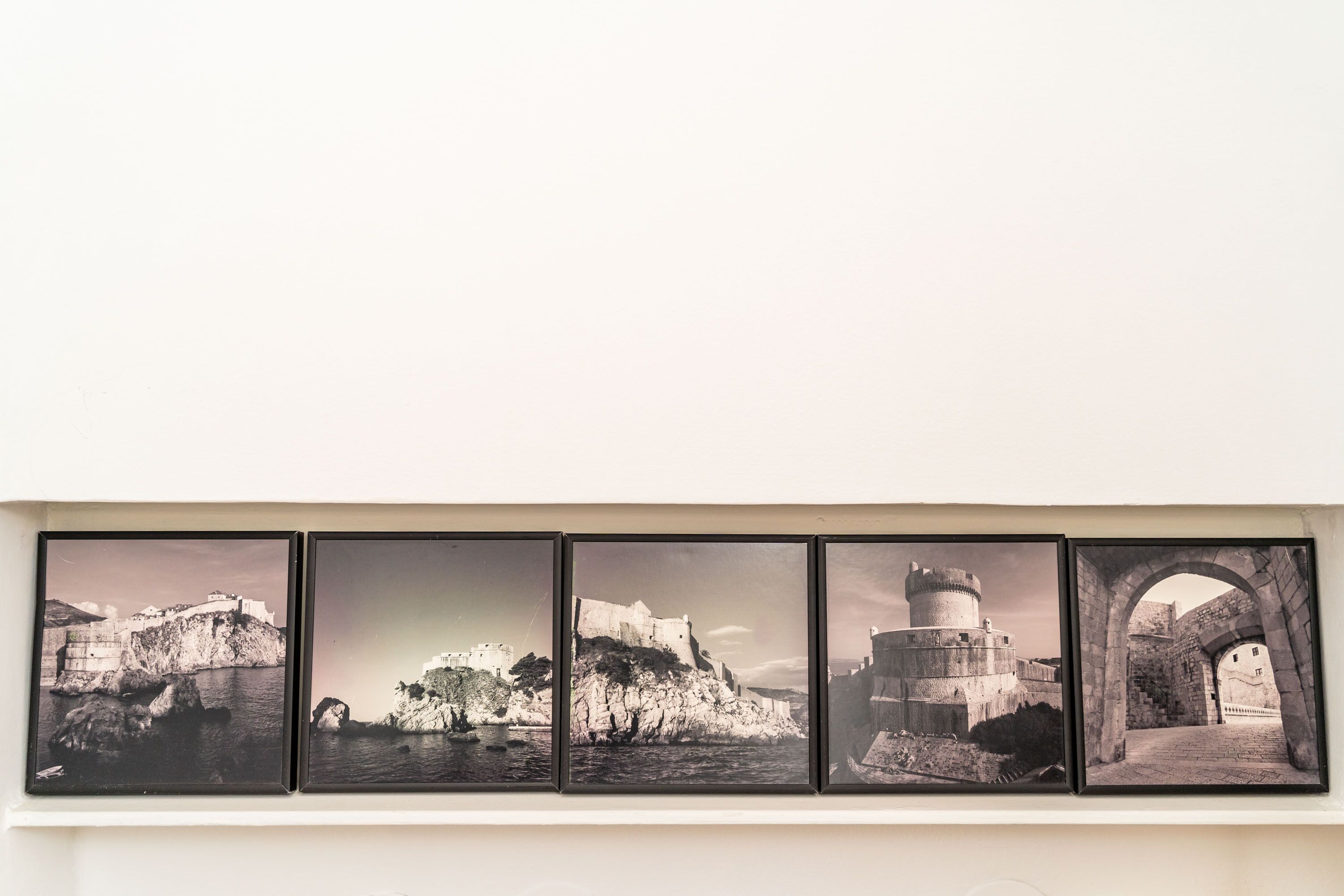 A wall-mounted triptych of black and white photographs depicting historical coastal fortifications.