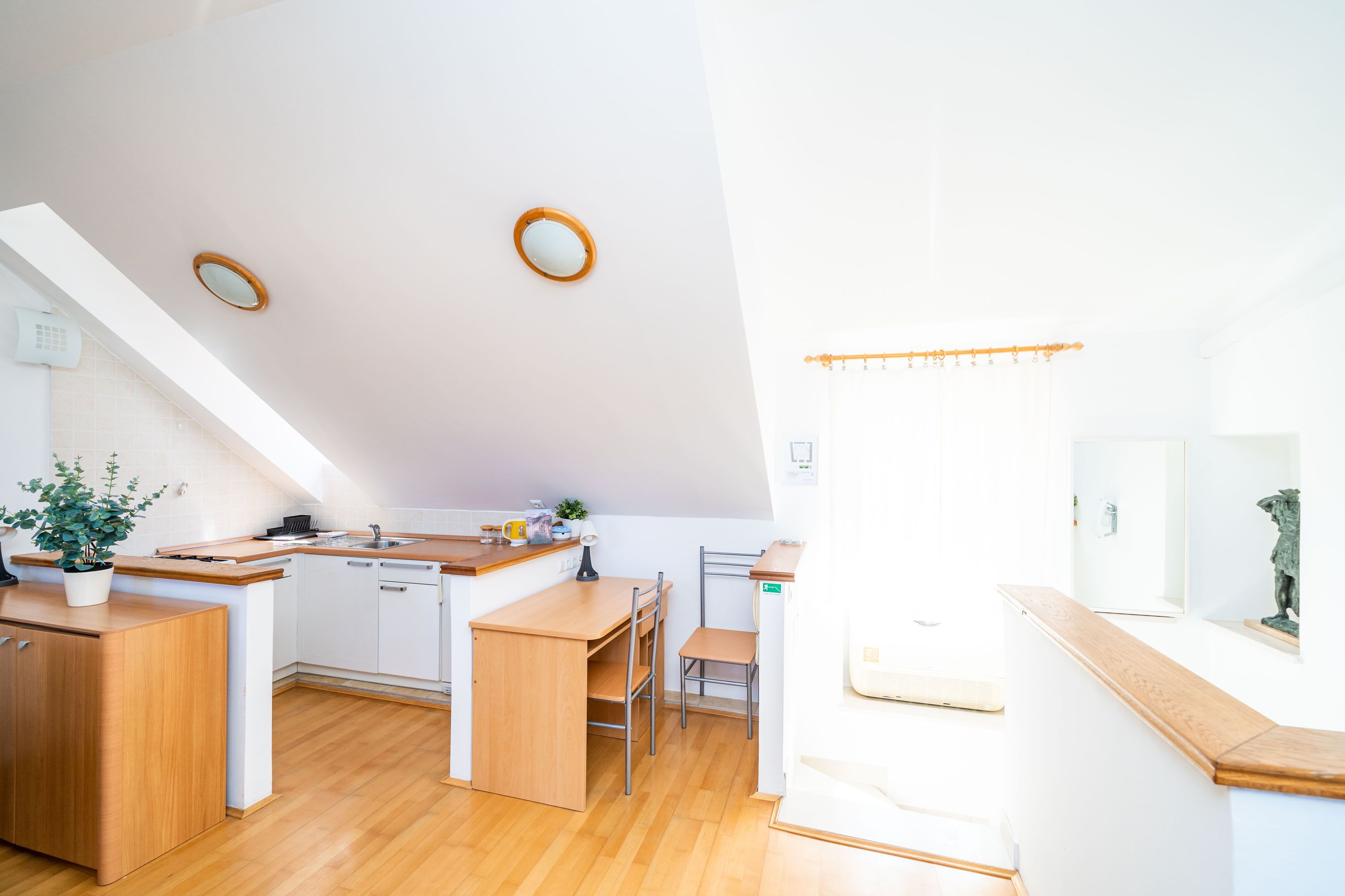Une cuisine moderne avec des meubles en bois, un îlot central et un coin repas équipé d’une chaise.