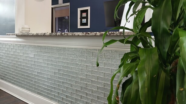 A kitchen with a tiled backsplash, a clock, and a Wi-Fi sign. - OYO Hotel Tallahassee Downtown (Tallahassee)
