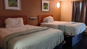 A hotel room with two beds, a nightstand, a wall-mounted lamp, and two framed pictures. - OYO Hotel Tallahassee Downtown (Tallahassee)
