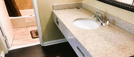 A bathroom with a granite countertop, a white sink, and a mirror.