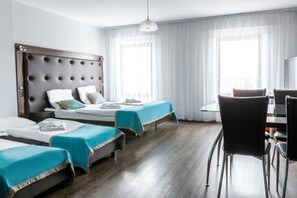 A hotel room with a large bed, two smaller beds, a desk, and a chair. - Hotel Opera (Tarnowskie Gory)