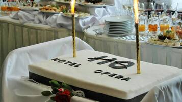Una mesa de hotel con un pastel que dice "HOTEL OPERA" y dos velas encendidas.