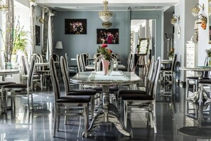 A dining area with a round table, chairs, and a vase with flowers. - Hotel Opera (Tarnowskie Gory)
